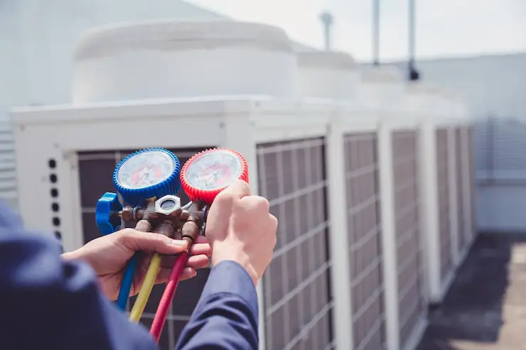 A close-up view of a technician's hands holding a manifold gauge set.