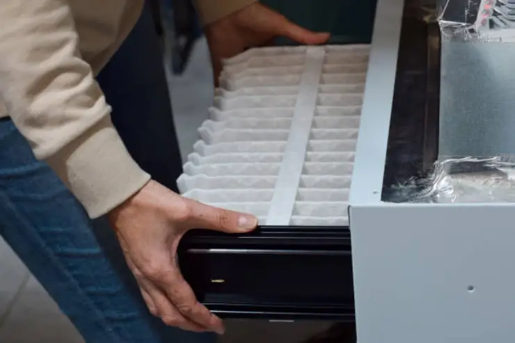 Close-up of a person holding a new, clean, pleated furnace filter.