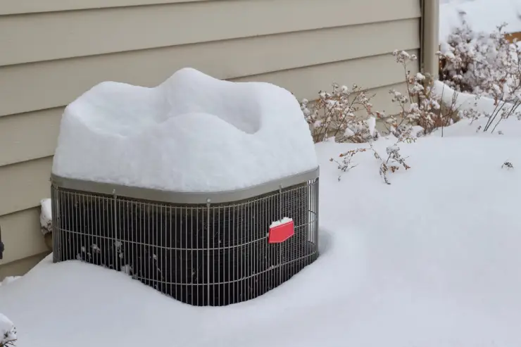 HVAC unit buried under a thick layer of heavy white snow.