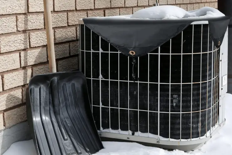HVAC unit with a protective top cover and a snow shovel.